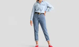 Modelka w jasnych jeansach z podwiniętymi nogawkami i jeansowej koszuli. Idealne jeansy dla niskiej osoby, które optycznie wydłużają nogi.
