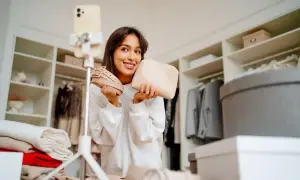 Uśmiechnięta influencerka prezentuje pasek i kosmetyczkę, wyznaczając nowe trendy.