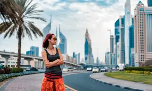 Turystka w Dubaju w pomarańczowej spódnicy i topie podziwia panoramę miasta.