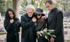 Smutna rodzina na cmentarzu. Elegancki ubiór damski na pogrzebie latem, z welurową marynarką i kapeluszem.