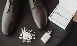 Eleganckie, brązowe oksfordy – jeden z klasycznych rodzajów butów męskich. Obok butonierka, obrączki i piersiówka.
