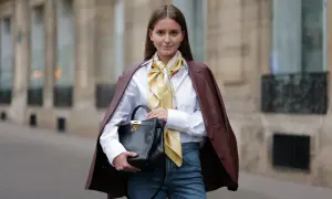 Elegancka kobieta pokazuje, jak nosić koszulę: biała koszula, jedwabny szal i bordowa marynarka.
