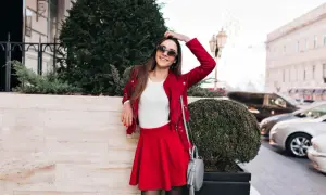 Elegancka stylizacja na mecz do strefy VIP: czerwona ramoneska, biały sweterek, krótka spódniczka i szara torebka.