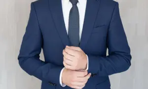 Mężczyzna poprawia mankiet granatowego garnituru na pogrzeb. Elegancki strój podkreśla powagę chwili.
