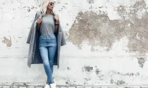 Modelka w jasnych jeansach skinny i szarym płaszczu. Dowiedz się, jakie jeansy do jakiej figury pasują najlepiej.