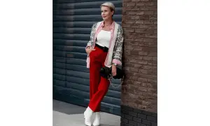 Elegancka kobieta w czerwonych spodniach damskich, białym topie, wzorzystej narzutce i białych botkach. Stylowa stylizacja na co dzień.