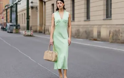 Miętowa sukienka na wesele, idealna na letnie przyjęcie. Elegancka, ale wygodna, z subtelną torebką w beżowym kolorze.