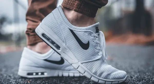 Białe buty sportowe Nike z czarnym logo. Dobre wsparcie dla stóp, idealne jako buty przy zapalenie rozcięgna podeszwowego.
