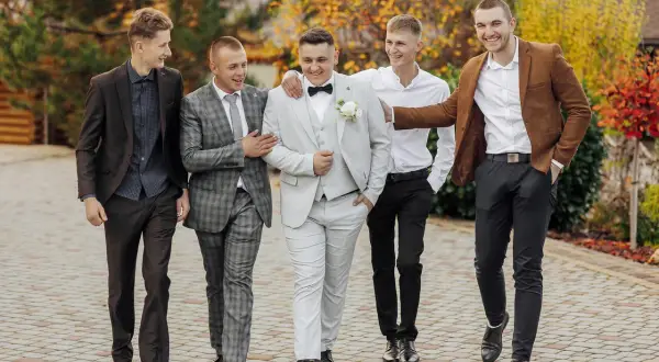 Pięciu mężczyzn w eleganckich garniturach i marynarkach, gotowych na męską stylizację na imprezę.