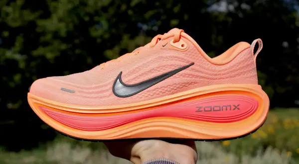 Pomarańczowy but sportowy z czarnym logo Nike i napisem ZoomX. Jedna z wielu marek butów, które oferują komfort i styl.