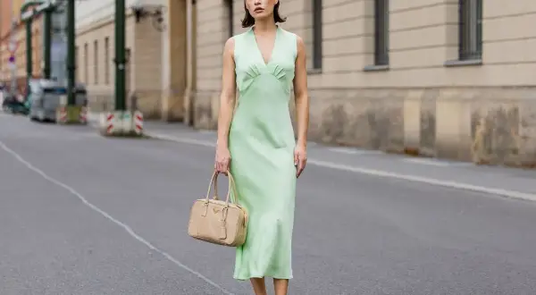 Miętowa sukienka na wesele, idealna na letnie przyjęcie. Elegancka, ale wygodna, z subtelną torebką w beżowym kolorze.