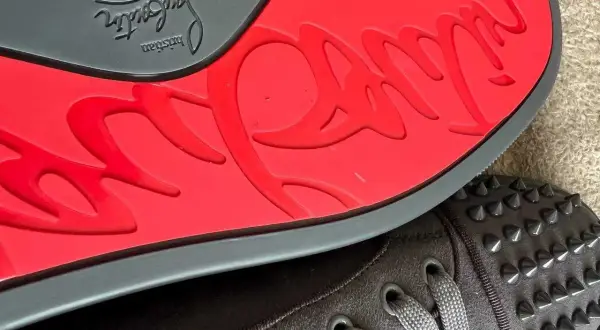 Czerwona podeszwa z logo Christian Louboutin i ćwieki na butach. Zastanawiasz się, ile kosztują buty Christiana Louboutina?