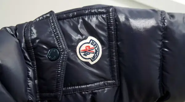 Granatowa, błyszcząca kurtka z naszywką Moncler. Czy to właśnie ta firma, o którą pytasz?