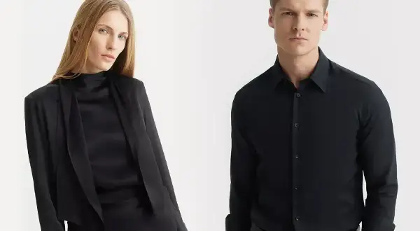 Elegancka kobieta w czarnej bluzce i marynarce, obok mężczyzna w czarnej koszuli. Jaka koszula do czarnych spodni? Klasyka zawsze się obroni.