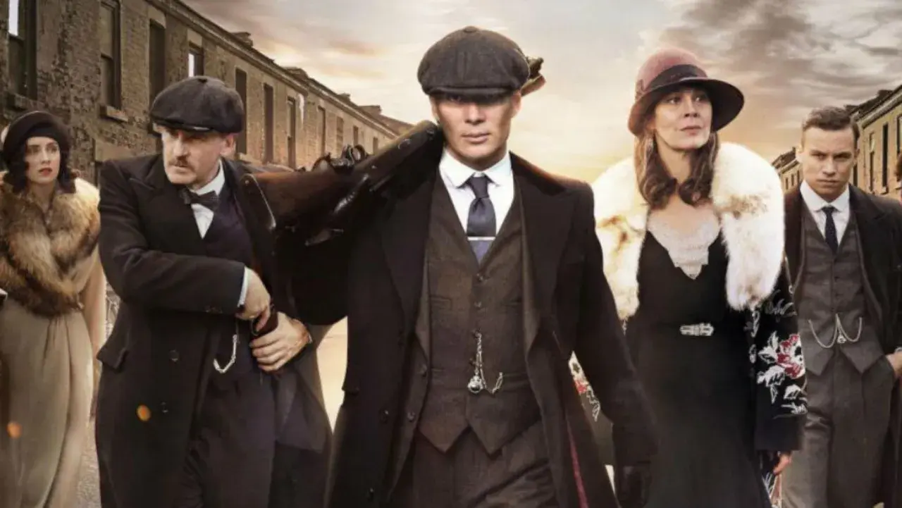 Gang w stylu Peaky Blinders, w tym Tommy Shelby z karabinem, idzie ulicą. Eleganckie płaszcze i kapelusze.