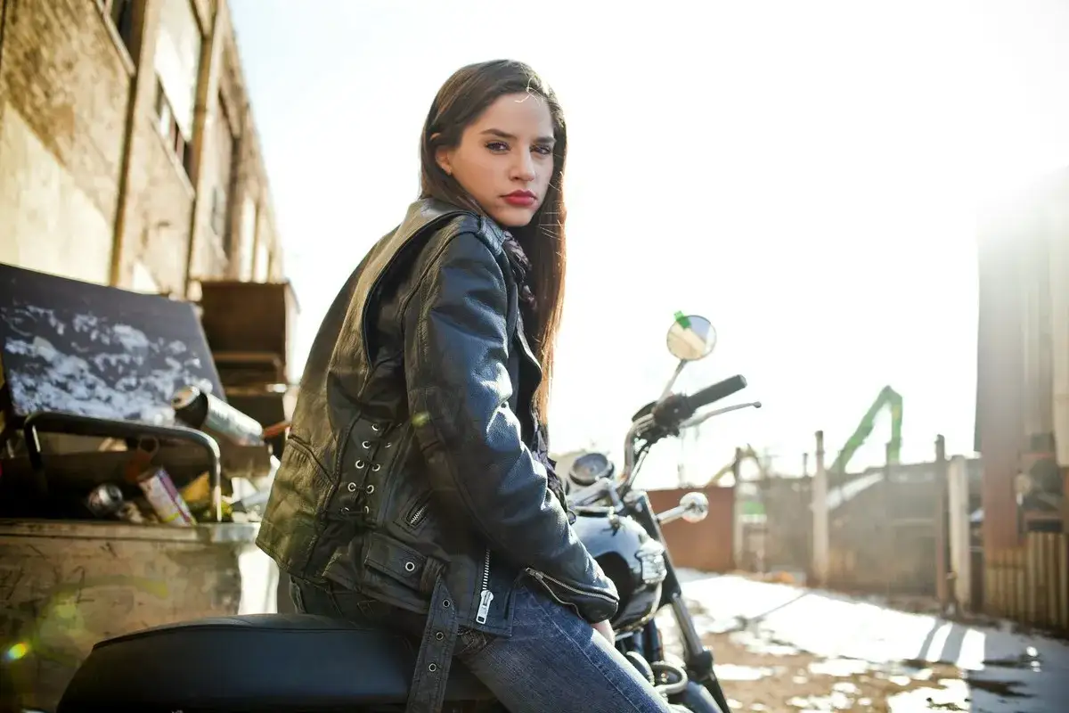 Dziewczyna w skórzanej kurtce i jeansach na motocyklu. Idealny strój, jak się ubrać na koncert rockowy, by poczuć się swobodnie i stylowo.