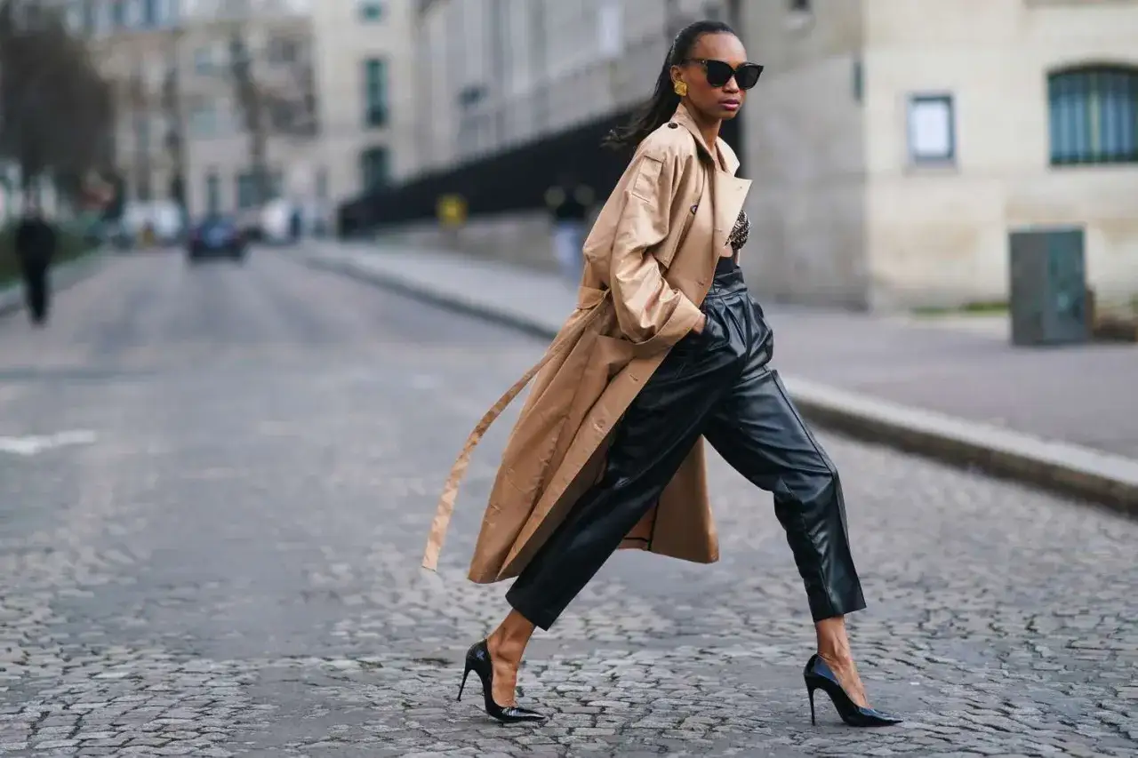 Elegancka kobieta w skórzanych spodniach i beżowym płaszczu. Zastanawiasz się, jaka bluzka do skórzanych spodni? Ten look pokazuje, że nawet top może być świetnym wyborem.