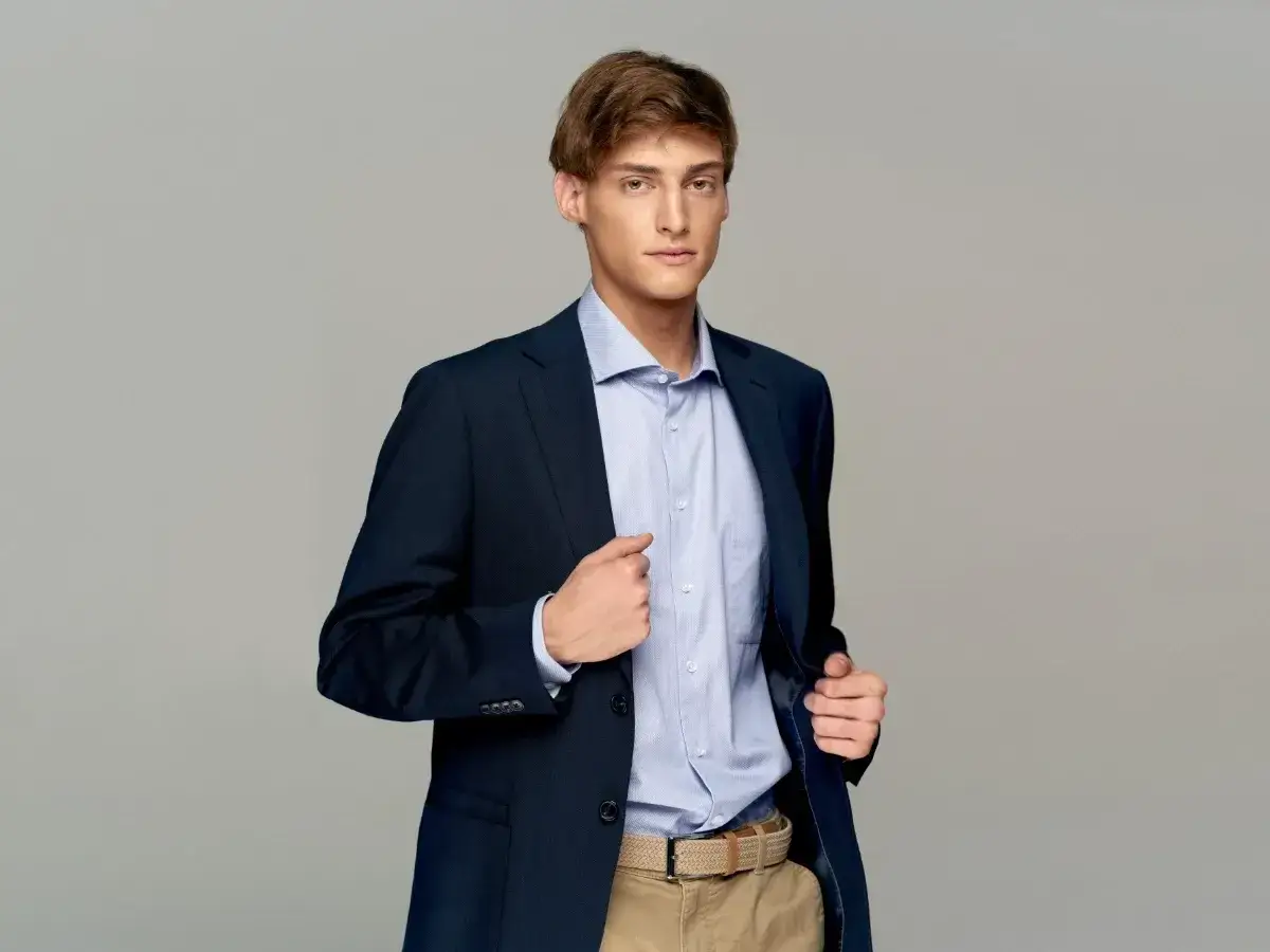 Młody mężczyzna w granatowej marynarce i błękitnej koszuli, gotowy na imprezę. Elegancka męska stylizacja na imprezę.